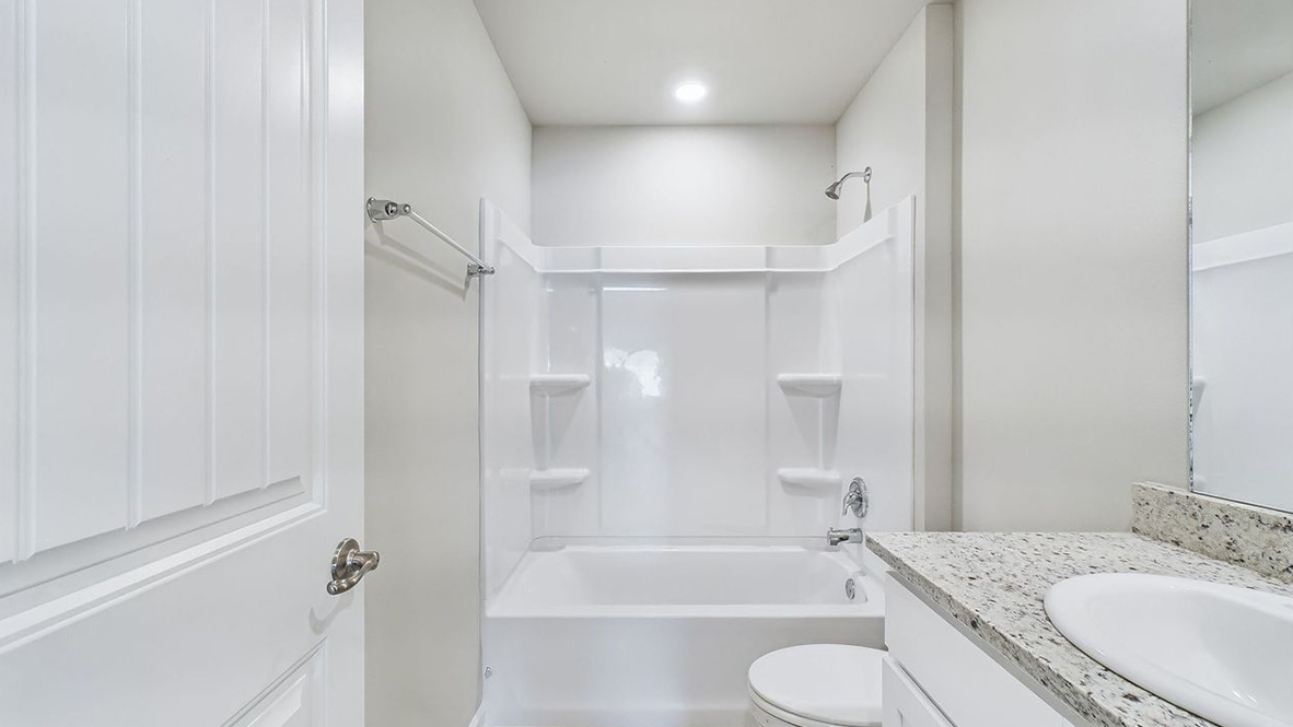 The single story Catahoula home plan bathroom has modern fixtures, closet space and granite countertops.