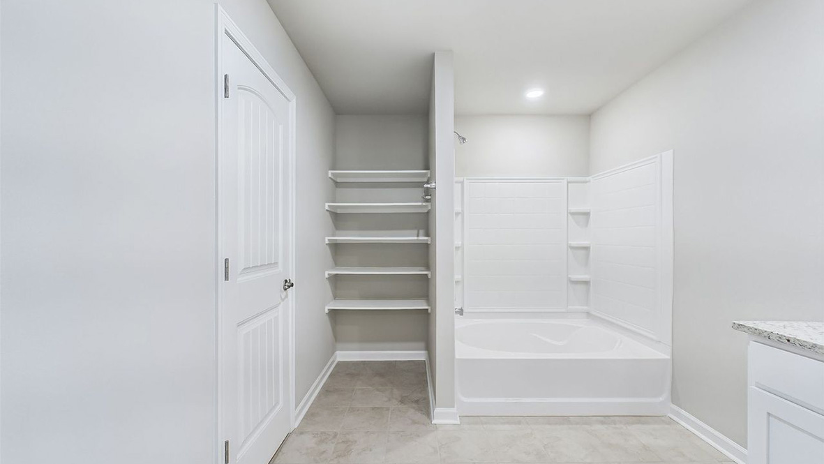 The single story Catahoula home plan bathroom has modern fixtures, closet space and granite countertops.