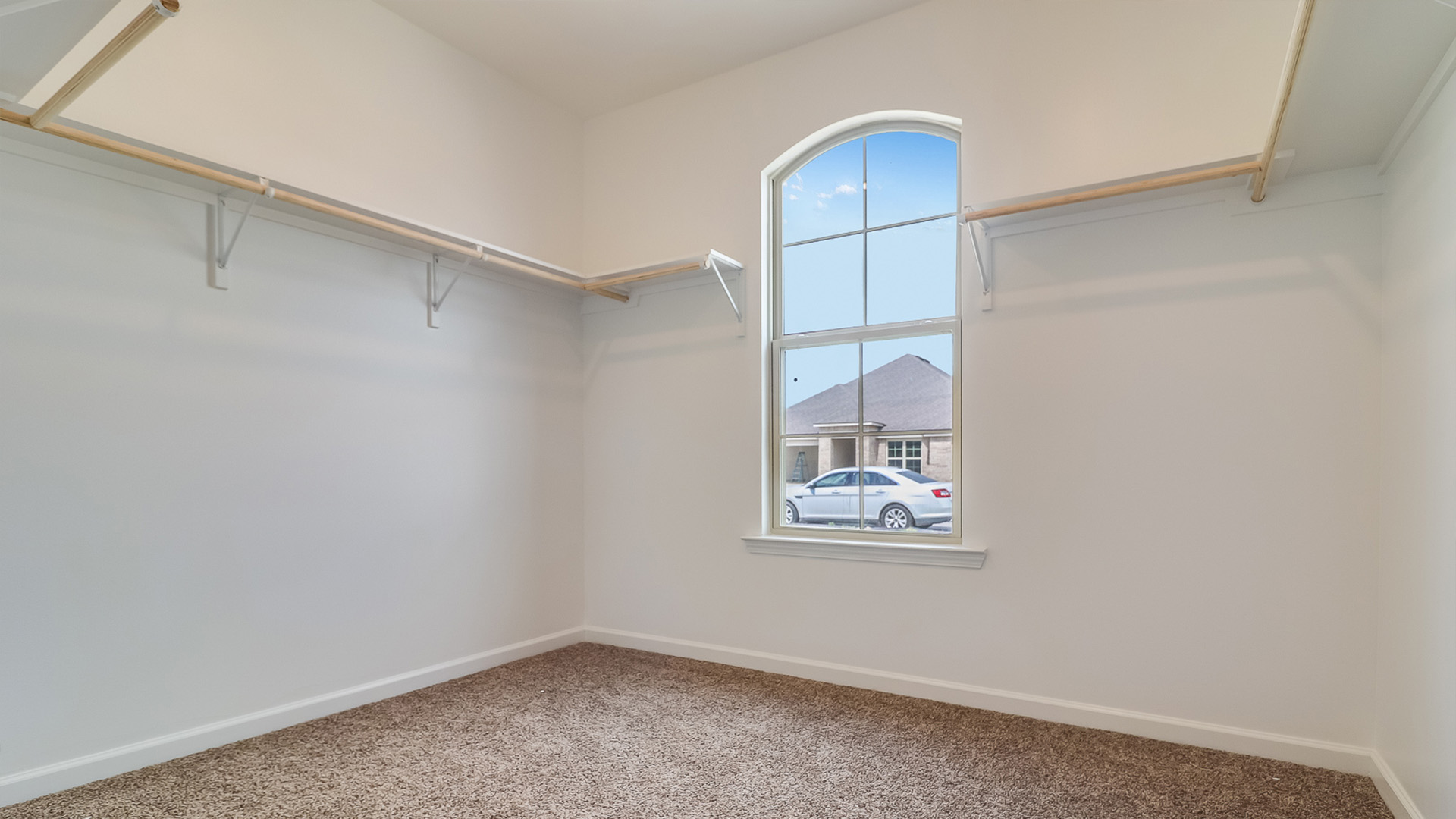 Spacious walk in closet with hanging rod and a window.
