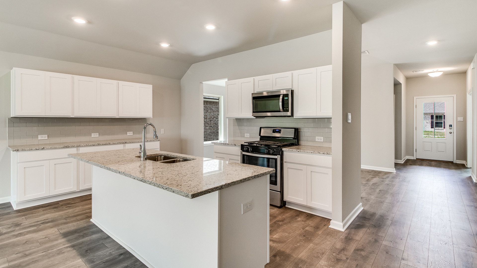 Kitchen showcasing new stainless steel appliances, cabinets, and countertops off the entryway.
