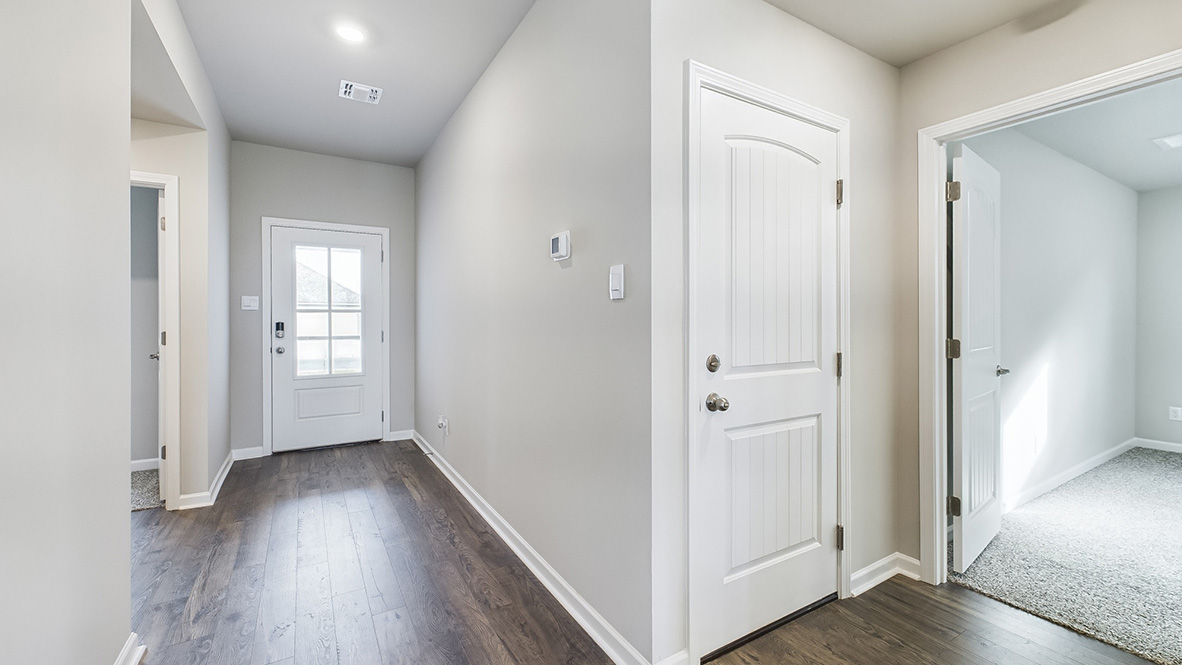 front entry way of home featuring brown flooring and beige walls