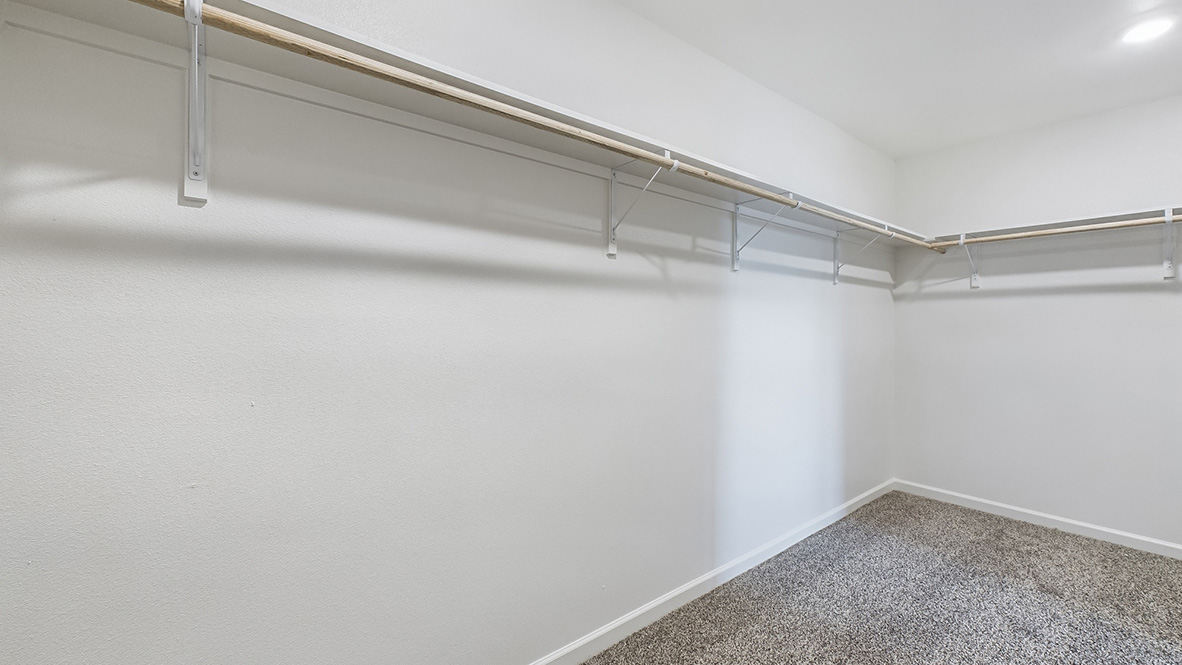Interior view of walk-in closet in the primary bedroom and spa-inspired ensuite in Hollis Heights, a new home by D.R. Horton