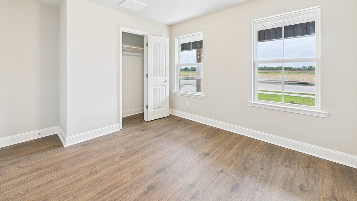 bedroom with brown flooring, beige walls and a window