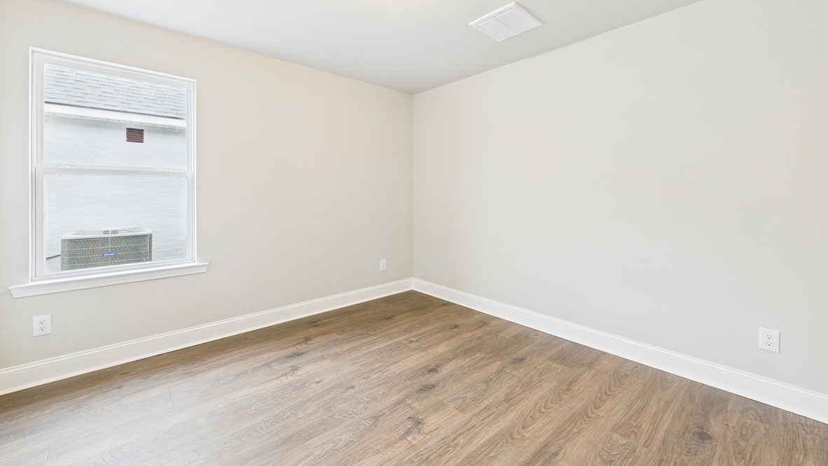 bedroom with brown flooring, beige walls and a window