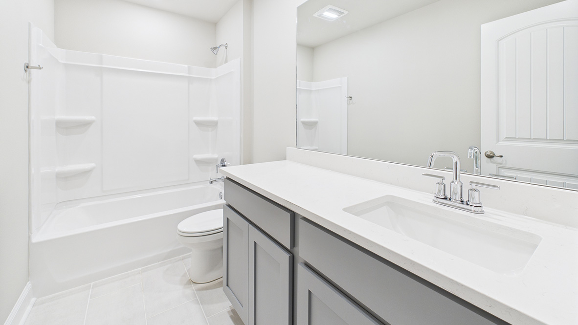 Family bathroom with stylish vanity, mirror, polished fixtures, cabinets, tub-shower combo in Ridgeland