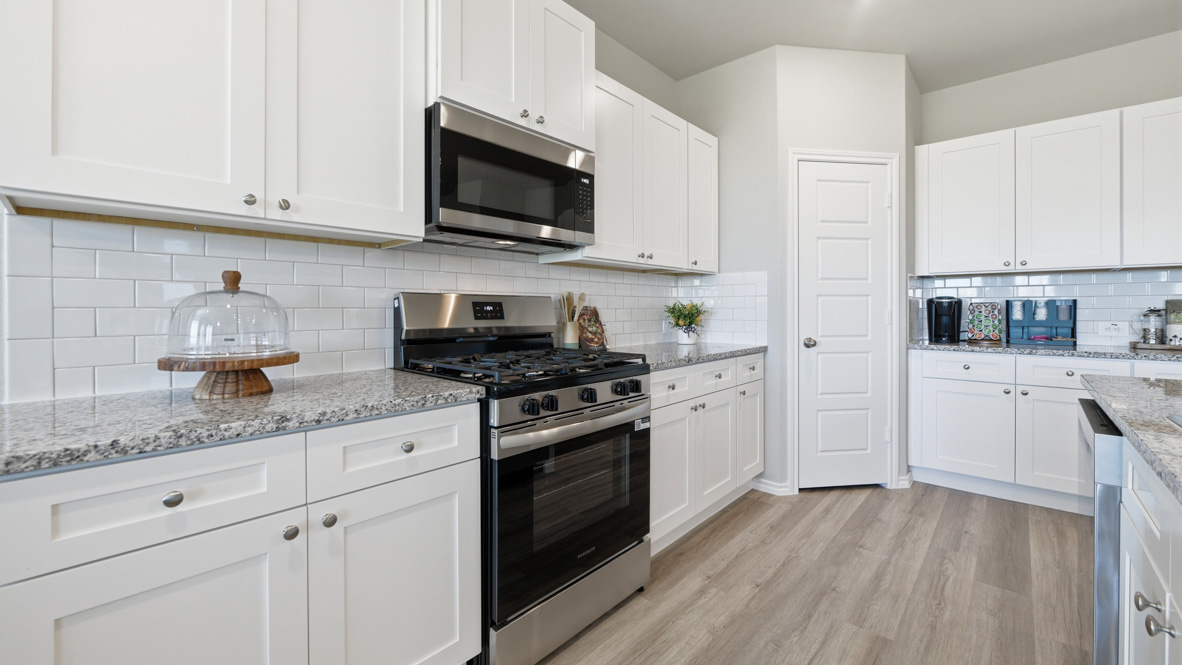 Bright kitchen with stainless steel appliances, tile backsplash, and luxurious countertops