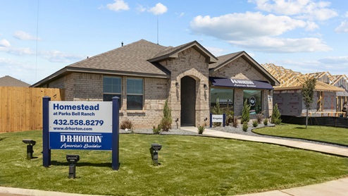 Side view of exterior tan brick model home with Homestead at Parks Bell Ranch community sign