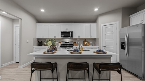 Kitchen peninsula with white cabinets and stainless steel appliances.