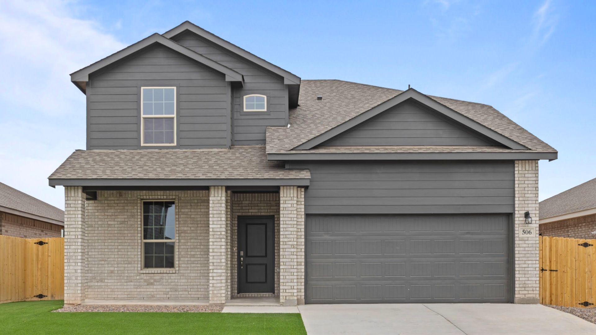 Exterior of two story modern brick single-family home with lush green grass and beautiful blue sky