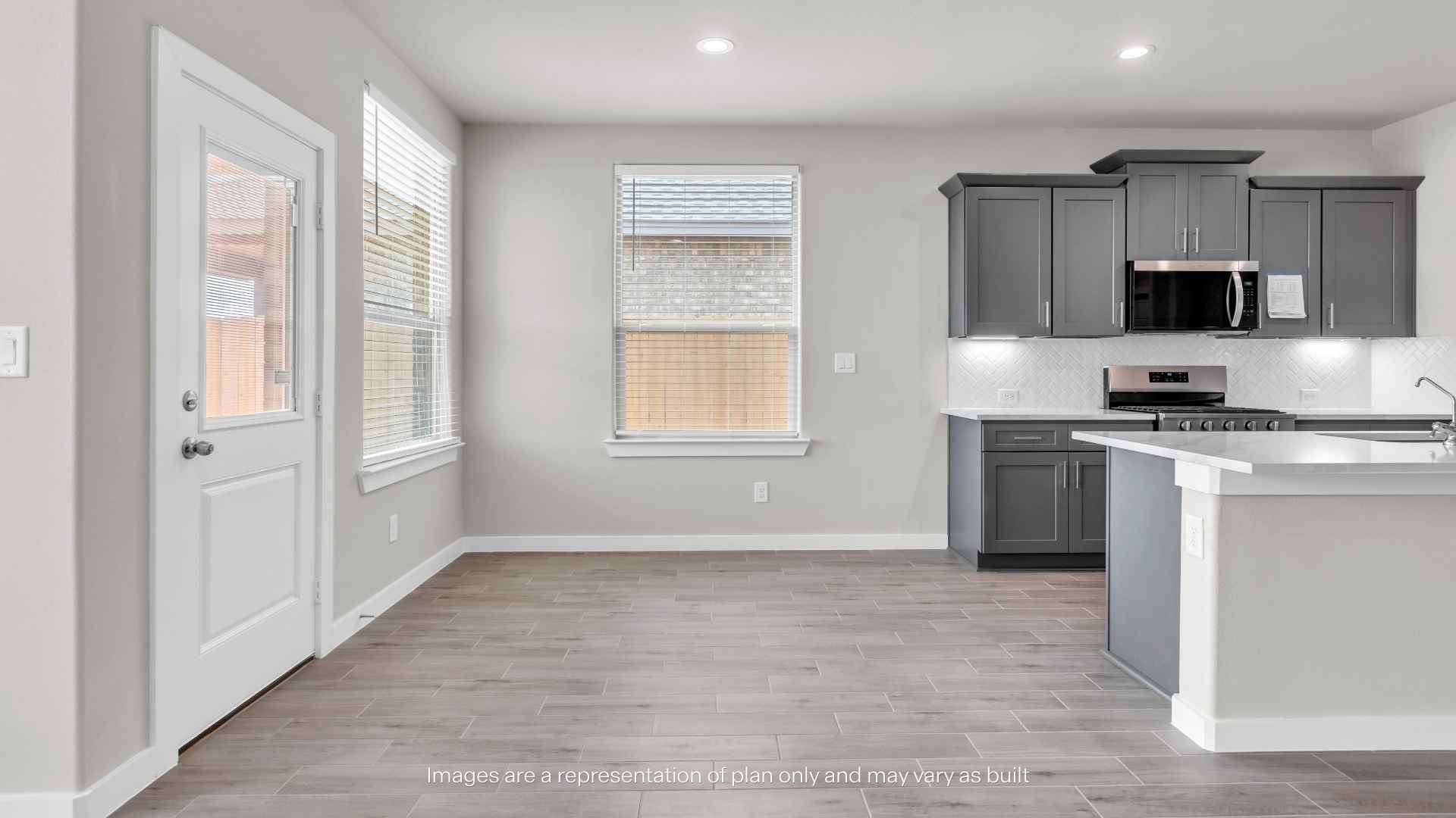 Open dining and kitchen area featuring wood-look tile flooring, gray shaker cabinets, white countertops, recessed lighting, a breakfast bar, and patio access through a glass-paneled door.