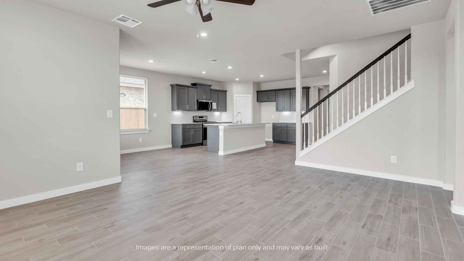 Spacious open-concept living area with wood-look tile flooring, light gray walls, recessed lighting, and a ceiling fan.