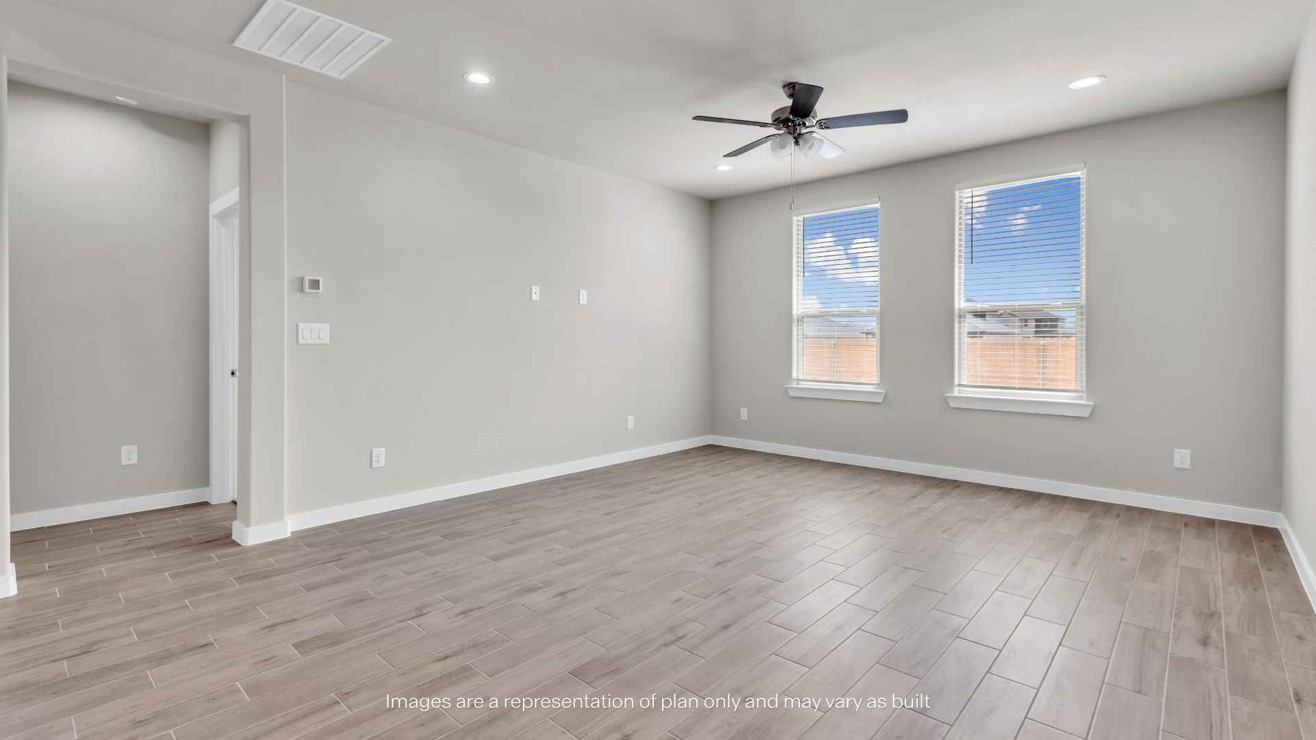 Open living area with tile flooring, ceiling fan, staircase, and modern kitchen with an island and gray cabinets.