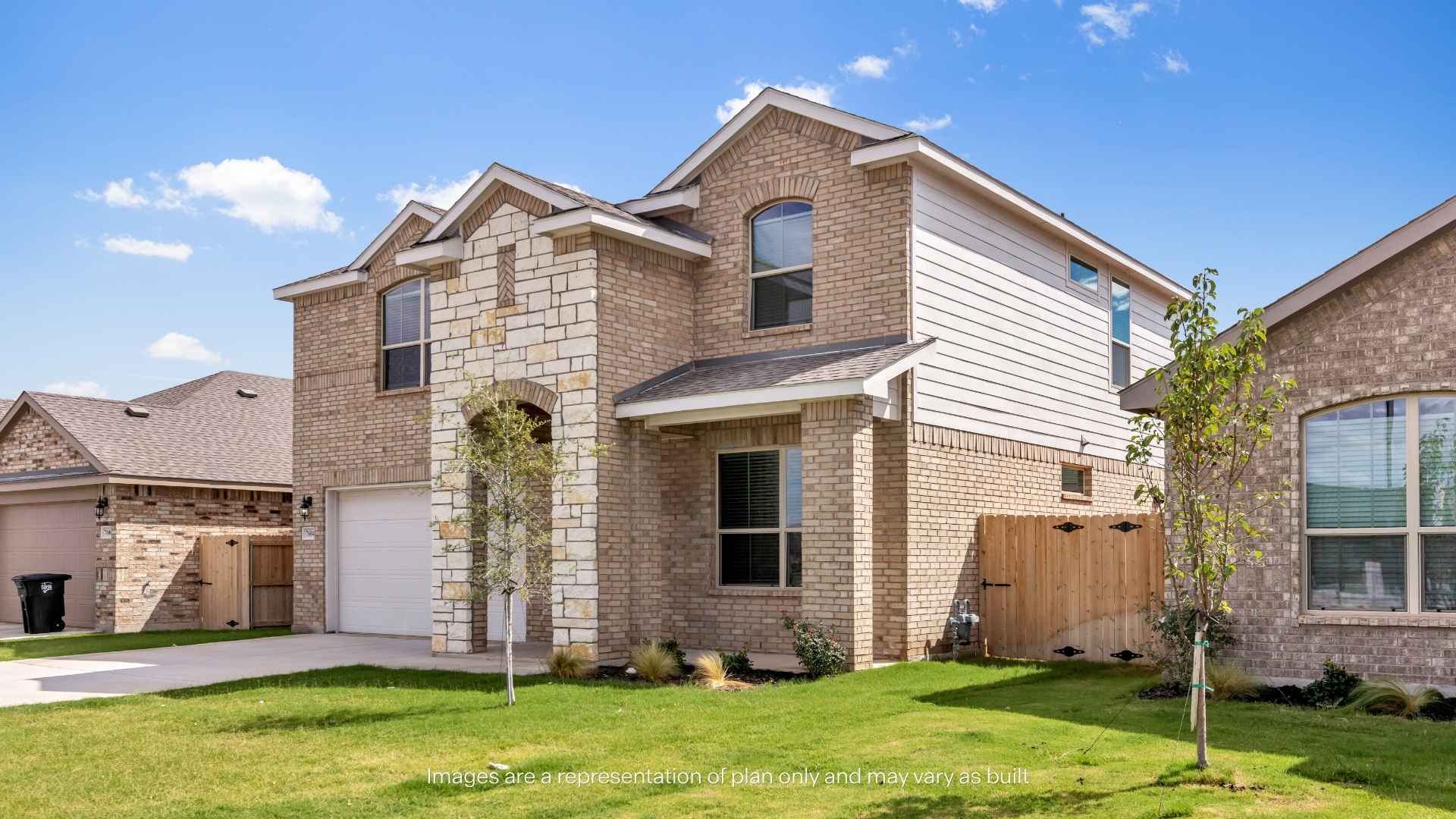 Angled exterior view of a two-story brick home featuring stone accents, covered front porch, two-car garage, green lawn, and wood privacy fence.