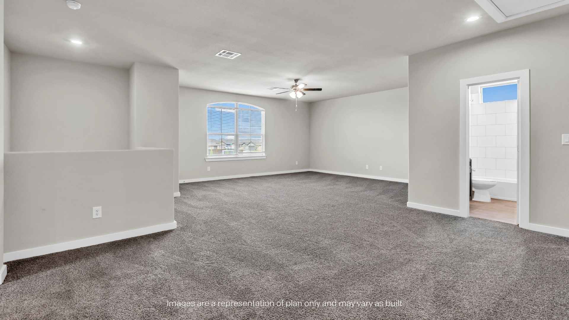 Large bonus room with carpet flooring, ceiling fan, and access to a full bathroom.