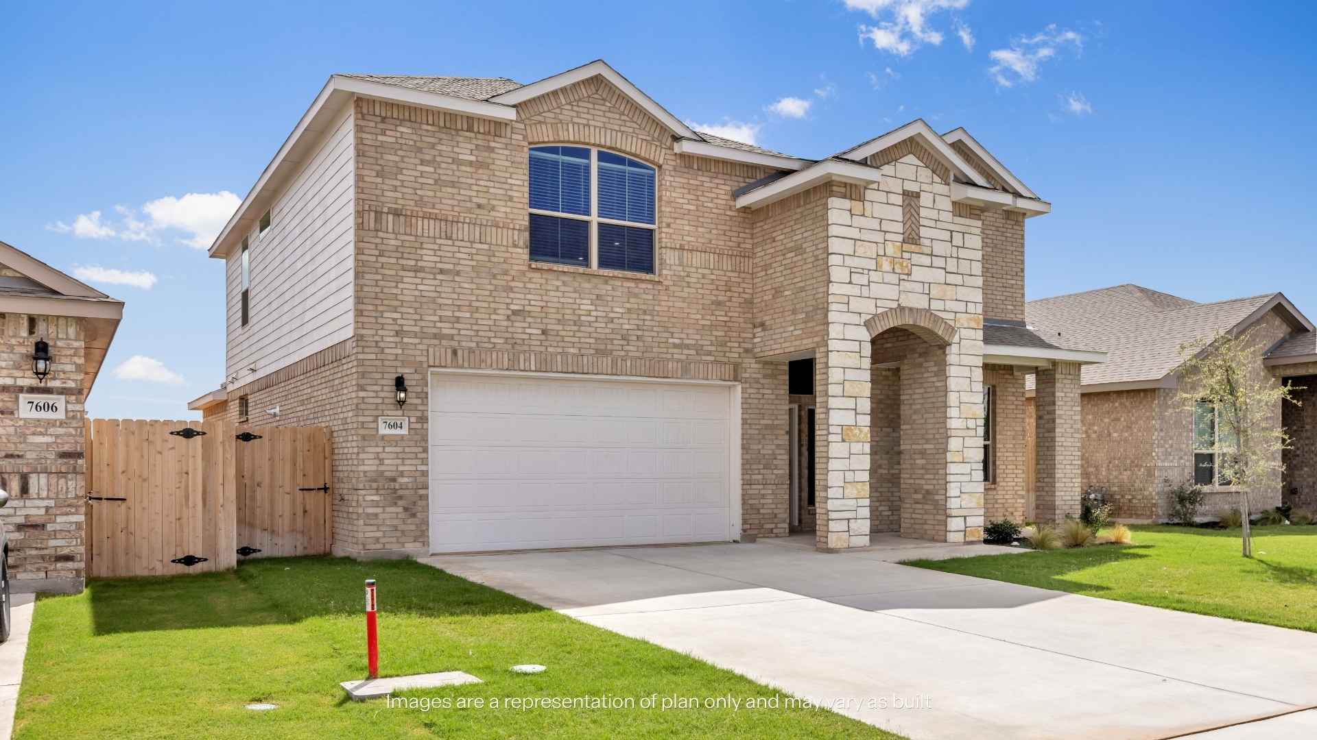 Side-angle exterior view of a two-story brick home with stone accents, covered porch, landscaped yard, young trees, and neighboring homes.