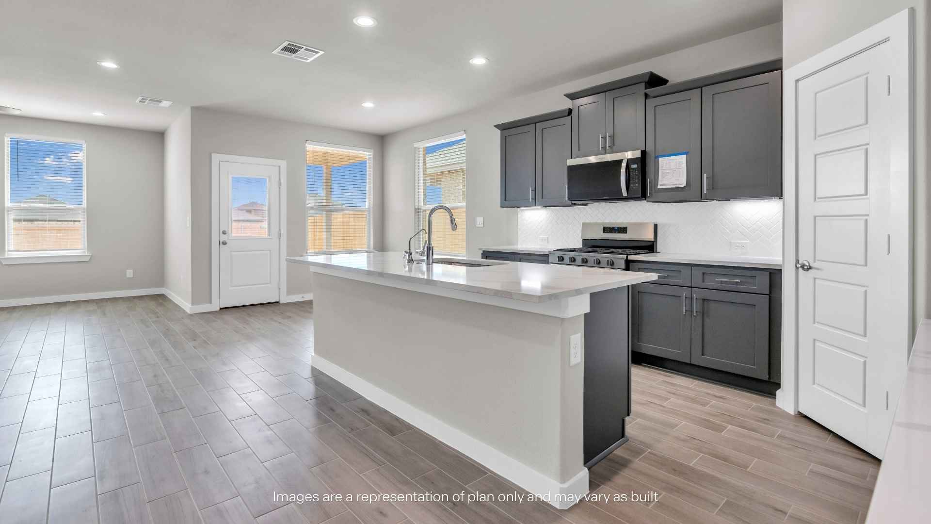 Open-concept kitchen and living area featuring a large island, gray cabinets, white countertops, stainless steel appliances, recessed lighting, and tile flooring.