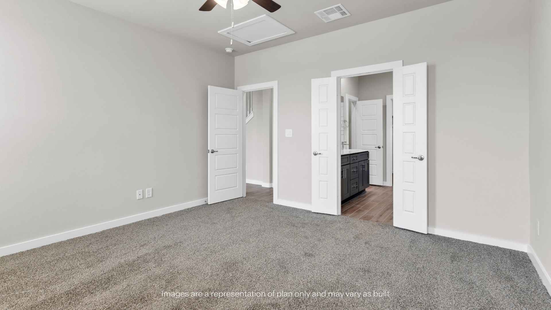 Primary bedroom with carpet flooring, ceiling fan, and access to the en-suite bathroom.