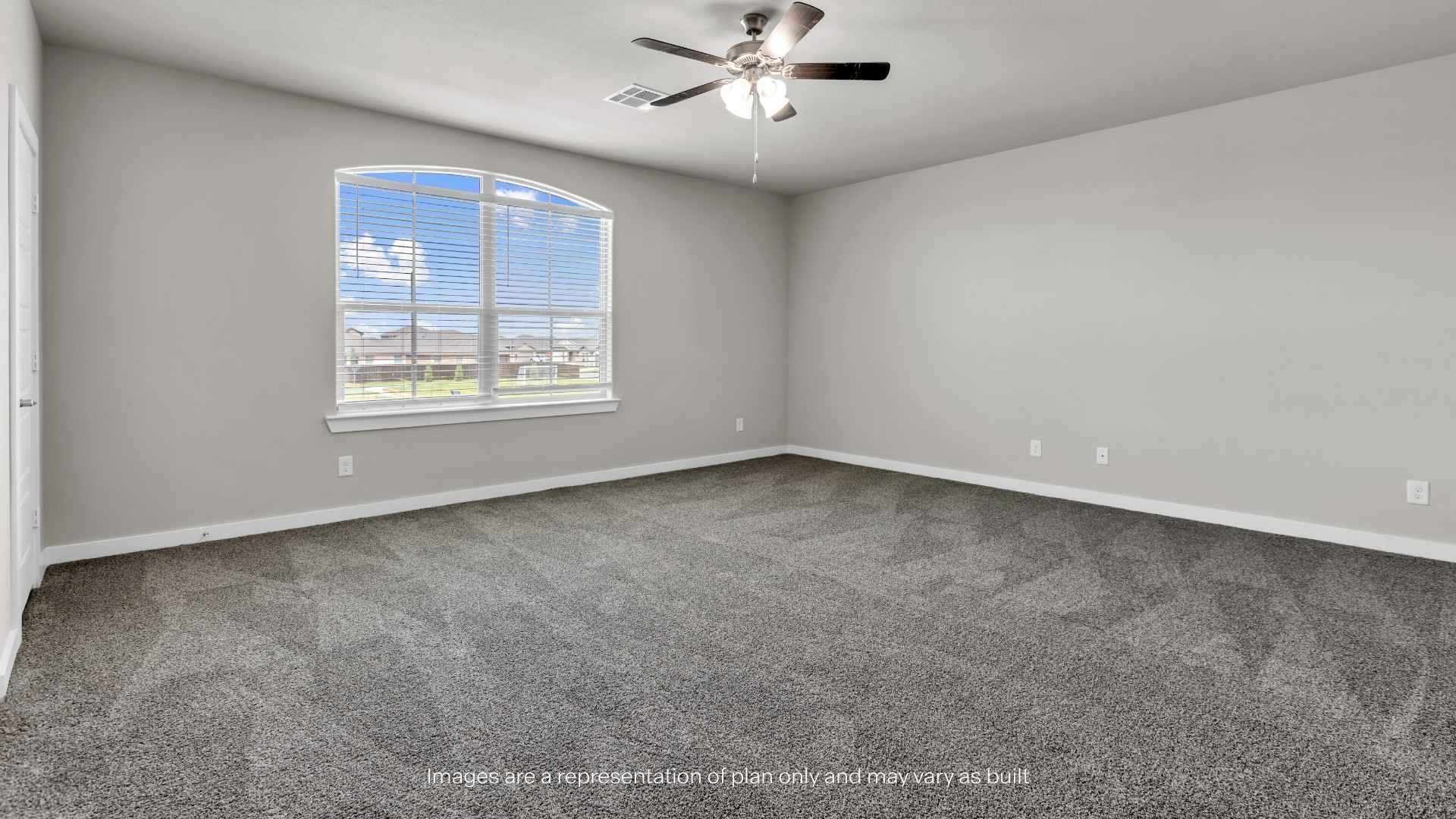 Large bonus room with carpet flooring, ceiling fan, and oversized window.