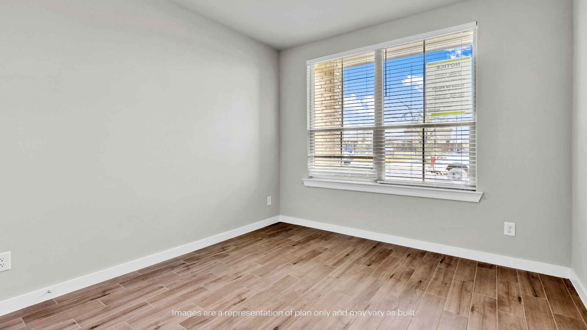 bedroom with light-colored walls, wood-look tile flooring, white trim, closet door, and an open doorway leading to the hall.