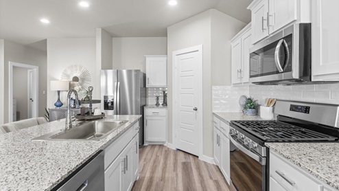 Open concept white kitchen with stainless steel appliances and granite countertops