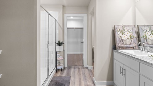 Private attached primary bathroom with tiled shower and vanity