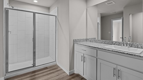 Primary bathroom with tiled shower and cultured marble vanity tops
