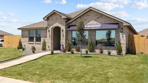 Side view of single-story modern brick home with lush front lawn