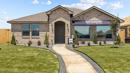Exterior view of single-story tan brick home with front porch entry, spacious walk-up, and lush green lawn