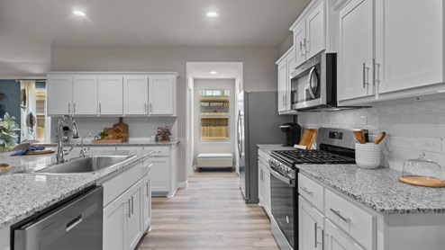 Spacious kitchen with quartz countertops, stainless steel appliances, and shaker style cabinets