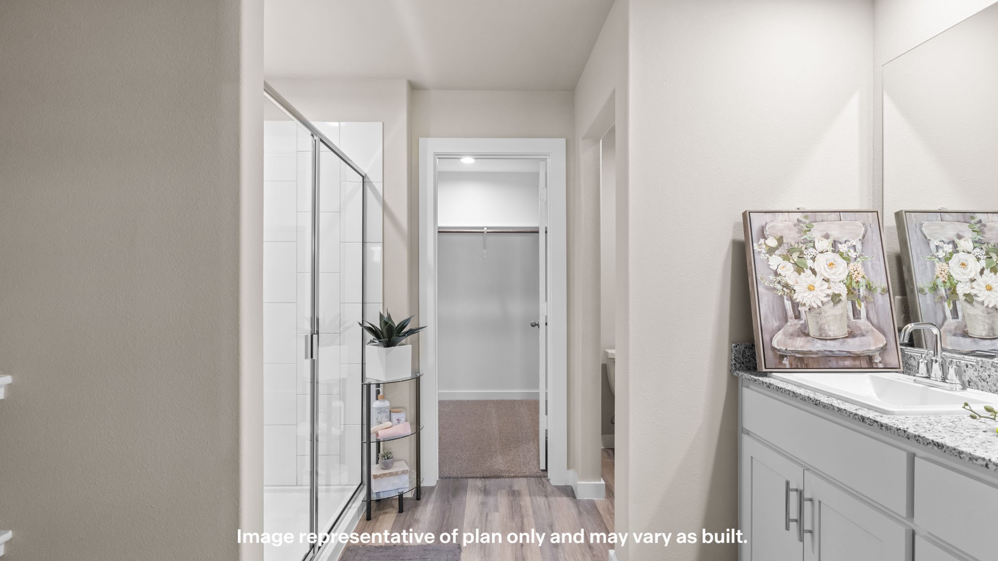 Private attached primary bathroom with tiled shower and vanity