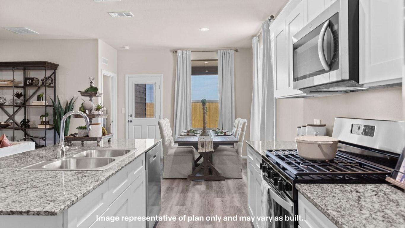 Modern kitchen with granite countertops, white cabinetry, and large island.