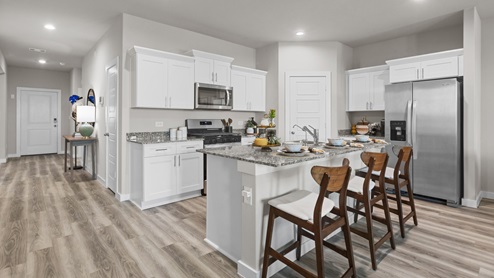 Interior white kitchen with spacious kitchen island and stainless steel appliances