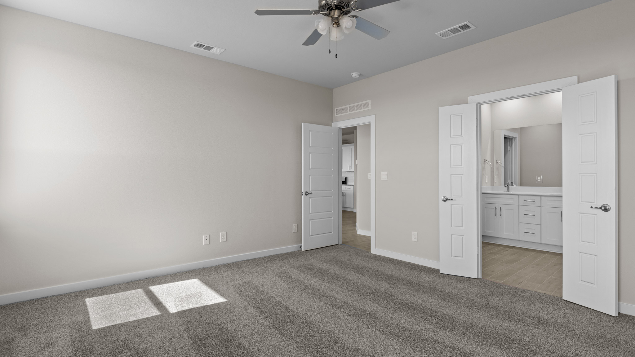 Spacious primary bedroom with plush carpet floors and private attached bathroom