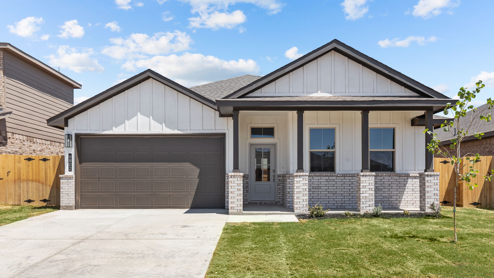 Exterior of single-story modern farmhouse style home with light siding and dark accents