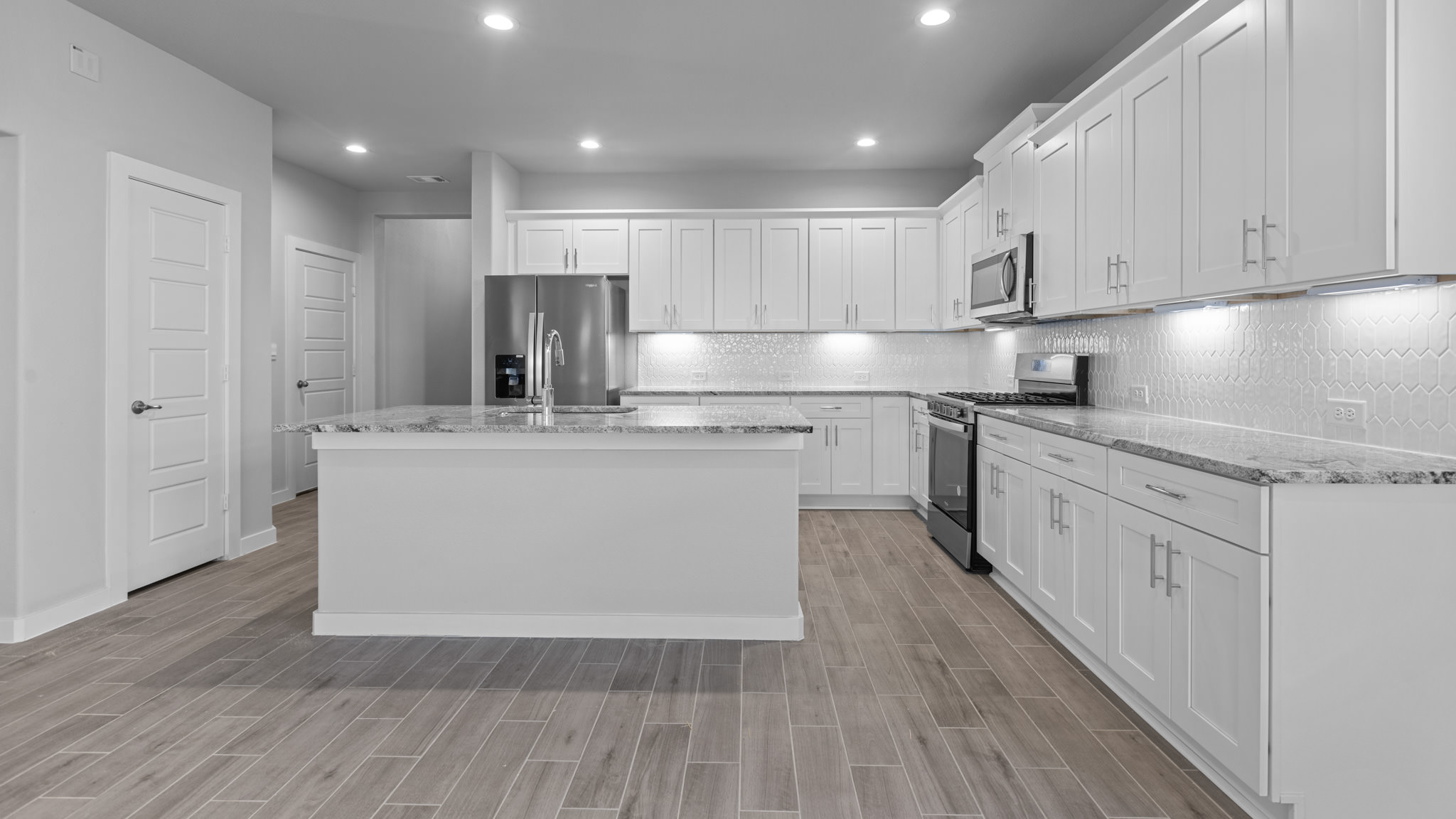 Open concept kitchen with stainless steel appliances, shaker style cabinets, and elevated finishes