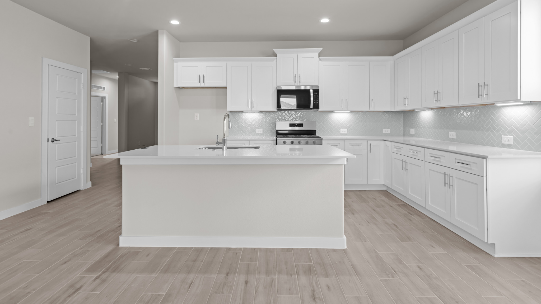 Open concept kitchen with stainless steel appliances, shaker style cabinets, and elevated finishes