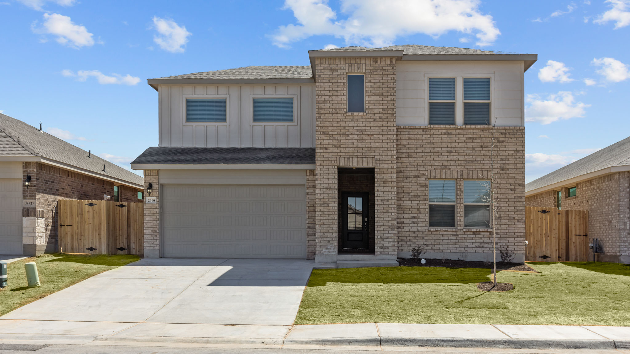 Exterior of modern two-story home with timeless brick and modern farmhouse style siding