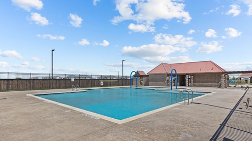 Blue community swimming pool with pool deck and swim shelf
