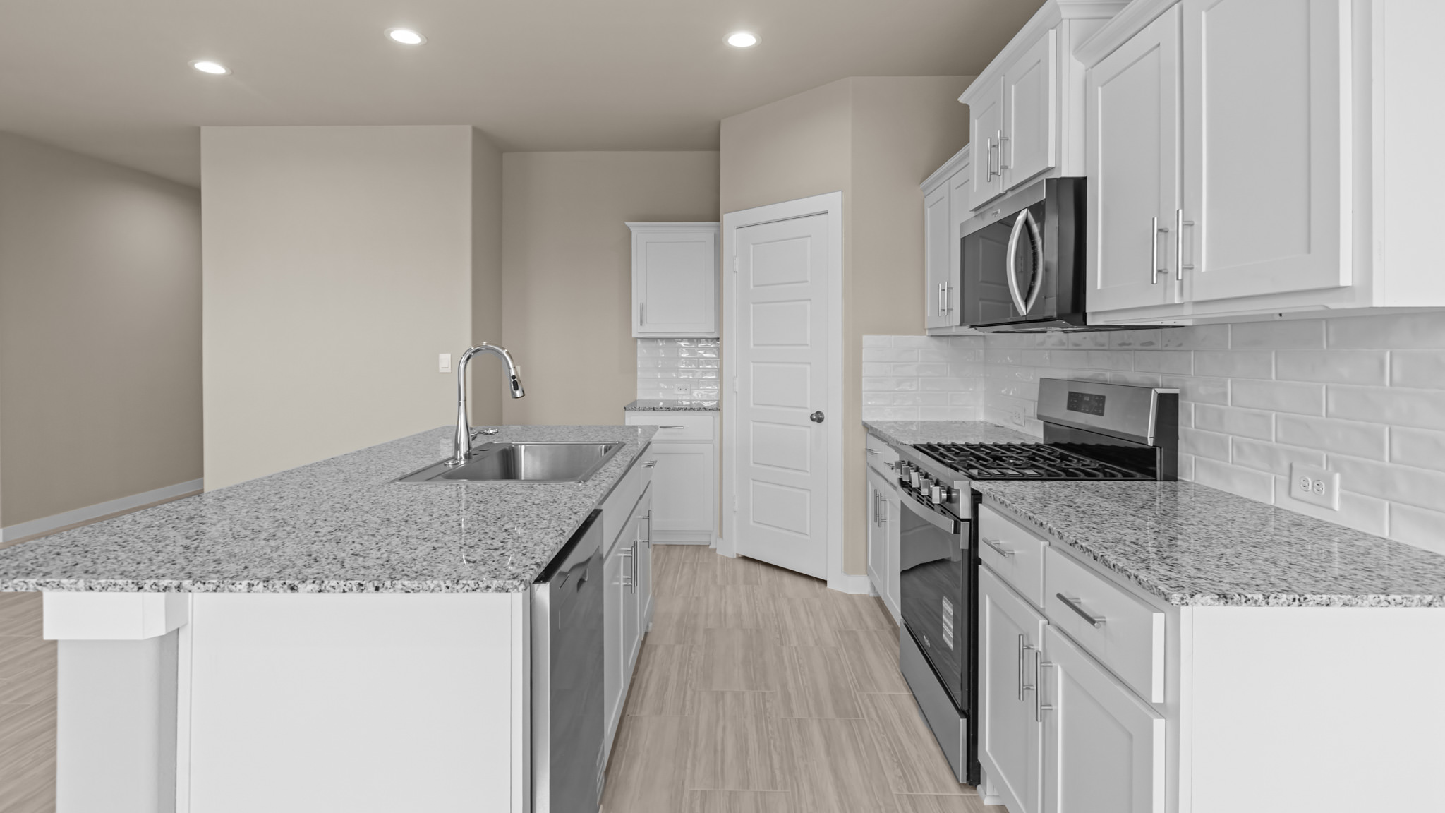 Open concept kitchen with stainless steel appliances, shaker style cabinets, and elevated finishes