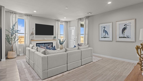 Open concept living and family space with cozy fireplace feature and ample natural lighting overlooking backyard