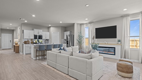 Bright open concept kitchen overlooking family and living room space with clean blue and gold accent colors