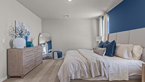 Primary bedroom with blue accent wall and details paired with clean bright white linens