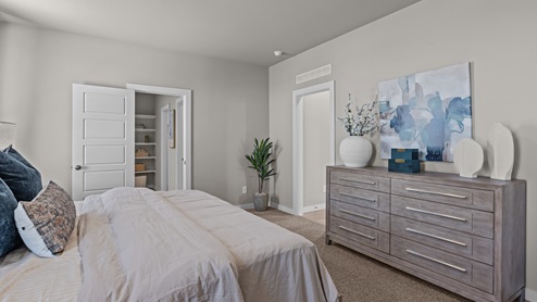 Bright primary bedroom with ample natural light and warm natural wood accent pieces paired with coastal blue hues