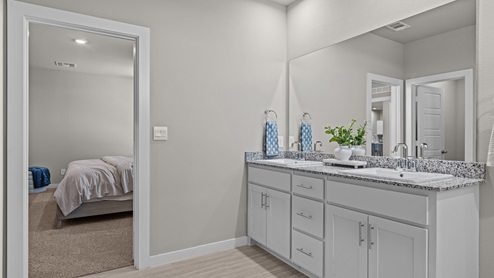 Primary bathroom attached to primary bedroom with built in vanity featuring double sinks