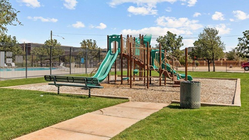 Fenced in community playground next to community pool area