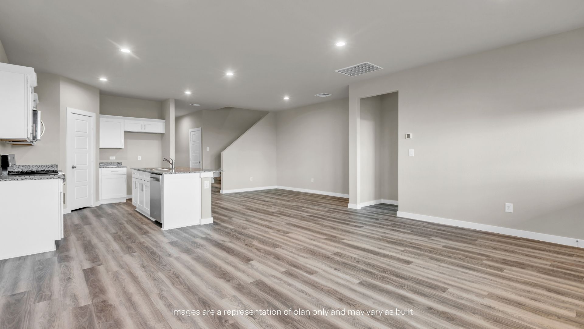 Open-concept kitchen with a large center island, granite countertops, white cabinetry, and modern finishes throughout.