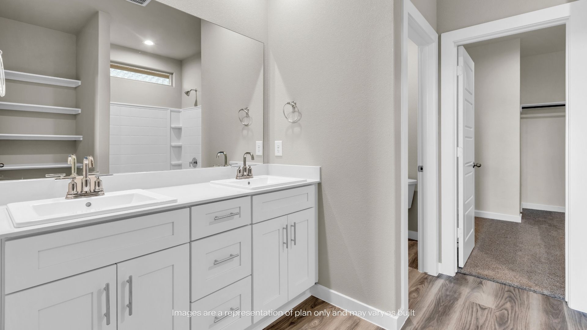 Spacious primary bathroom featuring a dual-sink vanity, oversized mirror, built-in storage shelving, and access to the walk-in closet.