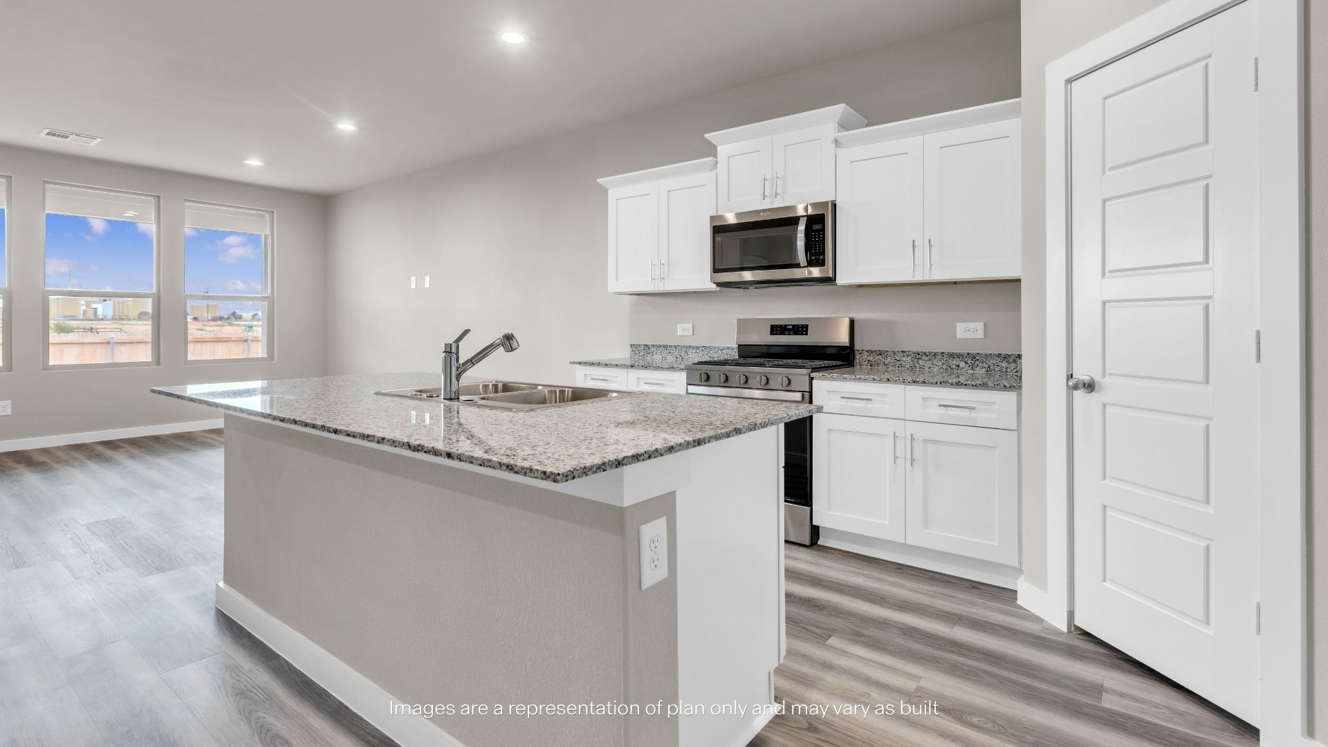 Spacious open living area with wood-look flooring, recessed lighting, and seamless flow to the kitchen and staircase.