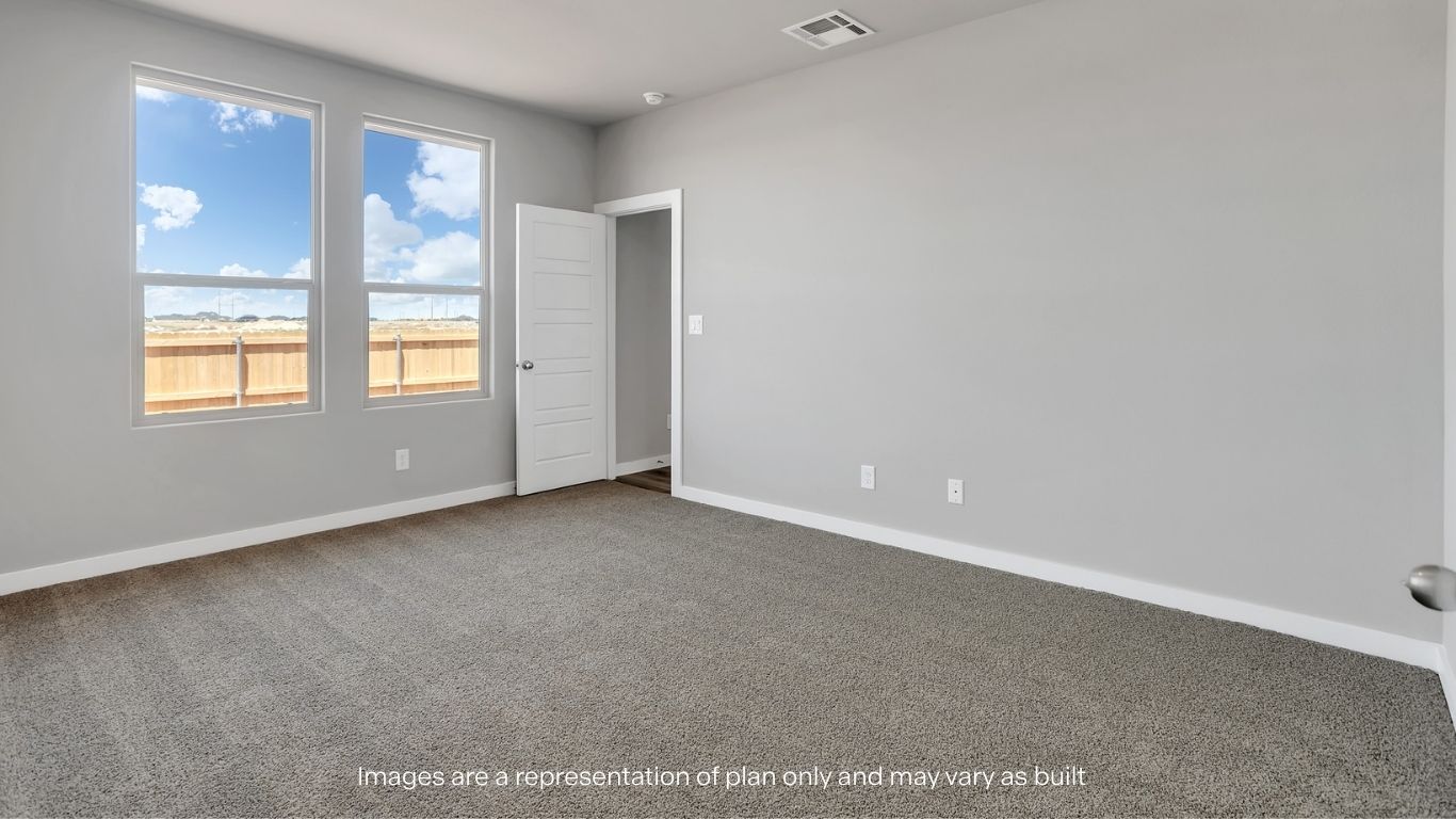 A cozy bedroom with soft carpeting and double windows overlooking the backyard.