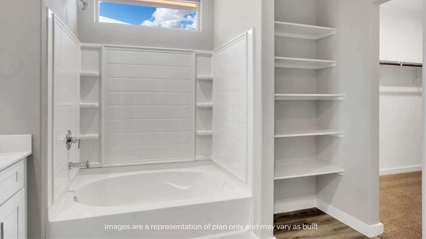 A bathroom view showcasing a deep tub and open shelving next to a walk-in closet.